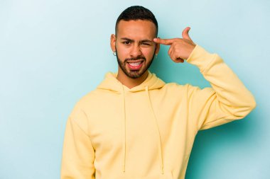 Mavi arka planda izole edilmiş genç İspanyol adam işaret parmağıyla bir hayal kırıklığı gösteriyor..