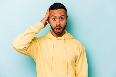 Mavi arka planda izole edilmiş genç bir İspanyol şoka uğruyor, önemli bir buluşmayı hatırlıyor..