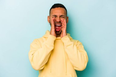 Genç İspanyol adam mavi arka planda izole edilmiş, heyecanlı bir şekilde bağırıyor..