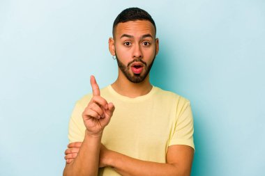 Latin kökenli genç bir adam mavi arka planda izole edilmiş. Harika bir fikri var, yaratıcılık kavramı..