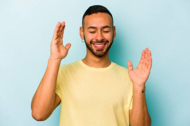 Genç İspanyol adam mavi arka planda izole edilmiş neşeli bir şekilde gülüyor. Mutluluk kavramı.