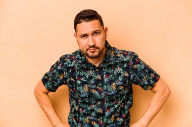 Genç İspanyol adam bej arka planda izole edilmiş üzgün, ciddi yüzlü, mutsuz ve hoşnutsuz..