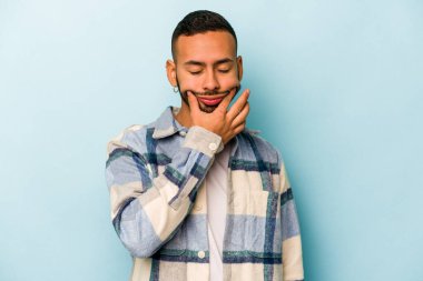 Latin kökenli genç bir adam mavi arka planda iki seçenek arasında kuşkulanıyor..