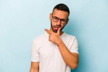 Latin kökenli genç bir adam mavi arka planda izole edilmiş. Bir strateji planlıyor, bir iş yolu düşünüyor..