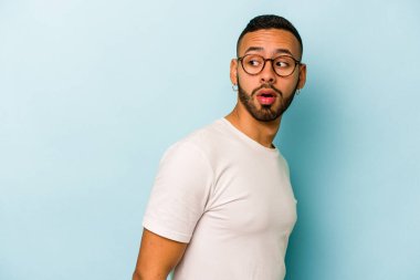 Mavi arka planda soyutlanmış genç bir İspanyol gülümsüyor, neşeli ve keyifli görünüyor..