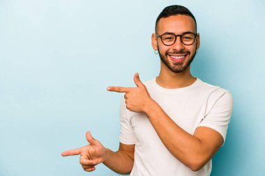 Mavi arka planda izole edilmiş genç bir İspanyol işaret parmaklarıyla işaret ederek heyecanlanıyor..