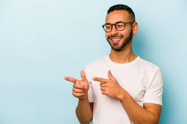 Genç İspanyol adam mavi arka planda izole edilmiş başparmak uzakta, gülüyor ve kaygısız.