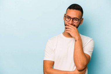 Genç İspanyol adam mavi arka planda izole edilmiş gülerek, kaygısızca, doğal duygularla.