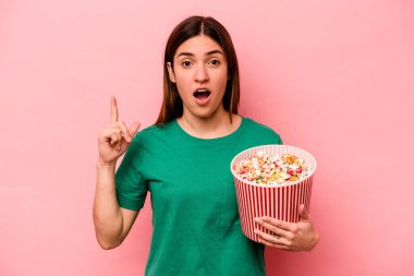 Pembe arka planda izole edilmiş patlamış mısır tutan beyaz bir kadının bir fikri var, ilham verici bir kavram..