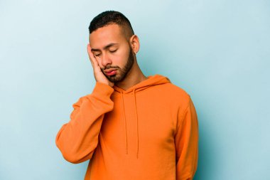 Mavi arka planda izole edilmiş genç bir İspanyol. Sıkılmış, yorgun ve dinlenmeye ihtiyacı var..