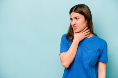 Kafkasyalı genç bir kadın mavi arka planda izole edilmiş kafasının arkasına dokunuyor, düşünüyor ve bir seçim yapıyor..