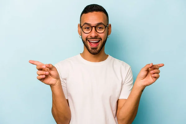 Jonge Spaanse Man Geïsoleerd Blauwe Achtergrond Wijzend Naar Verschillende Kopieerruimtes — Stockfoto