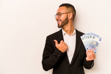 Latin kökenli genç bir adam elinde banknotlar tutuyordu. Beyaz arka planda izole edilmiş, baş parmak uzakta, gülüyor ve kaygısızdı..