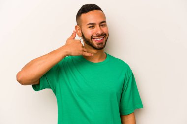 Beyaz arka planda izole edilmiş genç bir İspanyol, parmakları olan bir cep telefonu hareketi gösteriyor..