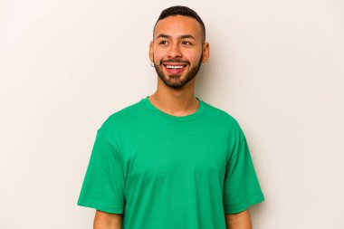 Beyaz arka planda izole edilmiş genç bir İspanyol. Rahatlamış ve mutlu bir şekilde gülüyor. Boynunda dişler var..