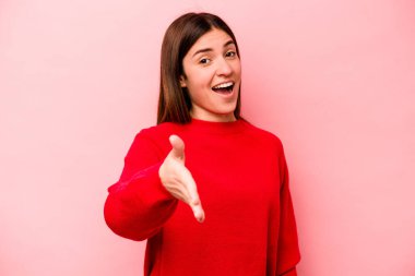 Pembe arka planda izole edilmiş beyaz bir kadın. Kameraya elini uzatıp selam veriyor..