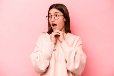 Pembe arka planda izole edilmiş genç beyaz bir kadın şans için dua ediyor, hayrete düşüyor ve ağzını açıp önüne bakıyor..