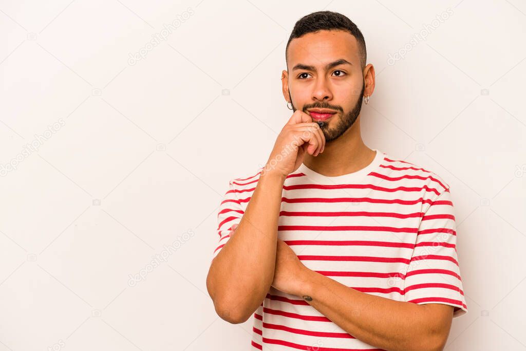 Young hispanic man isolated on white background relaxed thinking about something looking at a copy space.