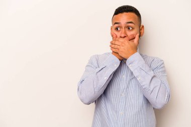 Genç İspanyol bir adam beyaz arka planda izole edilmiş. Düşünceli bir şekilde bir fotokopi odasına bakıyor. Ağzını eliyle kapatıyor..