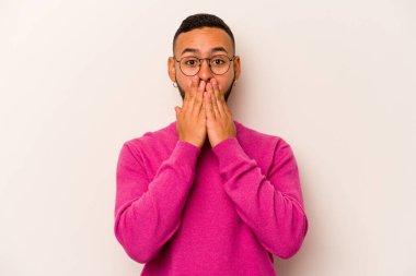 Beyaz arka planda izole edilmiş genç İspanyol adam elleriyle ağzını kapatırken şok oldu..