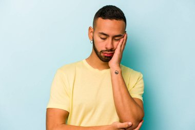 Mavi arka planda izole edilmiş genç bir İspanyol. Sıkılmış, yorgun ve dinlenmeye ihtiyacı var..