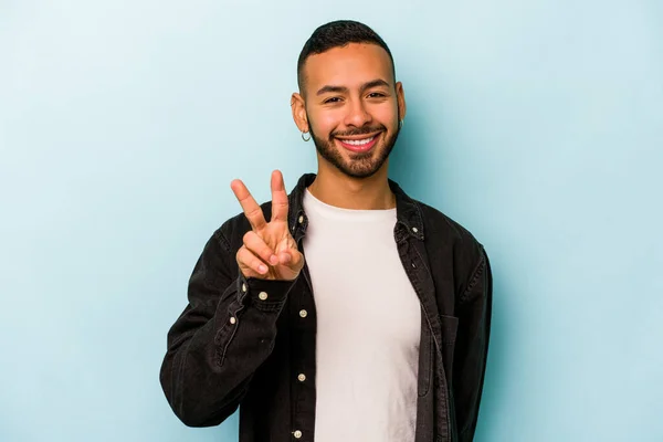 Mladý Hispánec Izolovaný Modrém Pozadí Ukazuje Znamení Vítězství Široce Usmívá — Stock fotografie