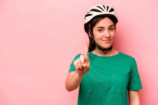 분홍색 배경에 고립된 헬멧을 코카서스 여자가 손가락으로 — 스톡 사진