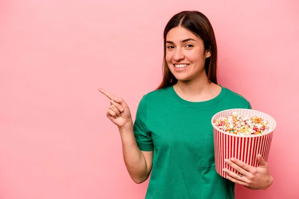 Jovem Caucasiana Segurando Pipoca Isolada Fundo Rosa Sorrindo Apontando Para — Fotografia de Stock