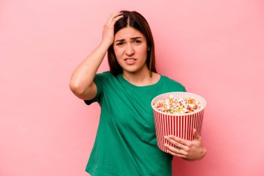 Pembe arka planda izole edilmiş patlamış mısır tutan genç beyaz kadın şok geçiriyordu, önemli bir toplantı hatırladı..