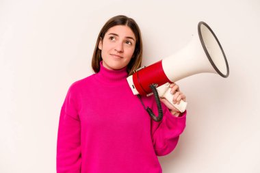Beyaz arka planda izole edilmiş bir megafon tutan genç beyaz kadın hedeflere ve amaçlara ulaşma hayali kuruyor.