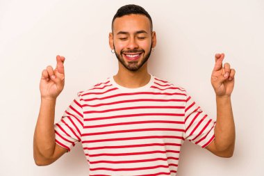 Latin kökenli genç bir adam beyaz arka planda izole edilmiş şans dilemek için şans diliyor.