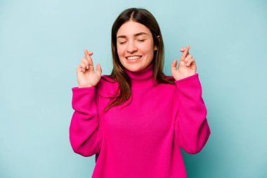 Genç beyaz kadın, mavi arka planda izole edilmiş şans dilemek için şans diliyor.