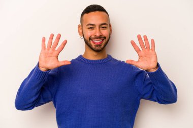 Beyaz arka planda izole edilmiş genç İspanyol adam on numarayı elleriyle gösteriyor..