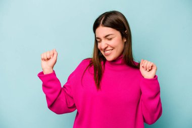 Genç beyaz kadın mavi arka planda izole edilmiş dans ediyor ve eğleniyor..