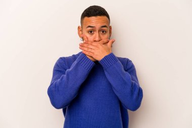 Beyaz arka planda izole edilmiş genç İspanyol adam elleri endişeli bir şekilde ağzı örtüyor..