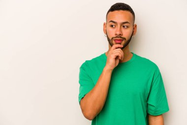 Beyaz arka planda izole edilmiş genç İspanyol bir adam rahatlamış bir şeyin fotokopi odasına baktığını düşünüyor..