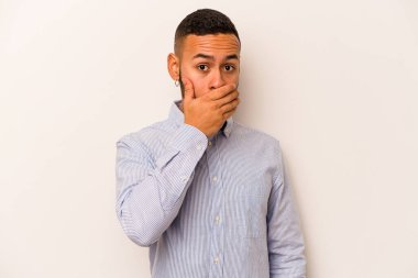 Beyaz arka planda izole edilmiş genç İspanyol adam elleri endişeli bir şekilde ağzı örtüyor..