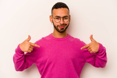 Beyaz arka planda izole edilmiş genç bir İspanyol gömlek fotokopi alanını elle işaret ediyor, gururlu ve kendinden emin.