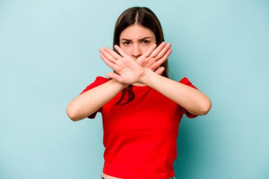 Mavi arka planda izole edilmiş genç beyaz bir kadın inkar jesti yapıyor.