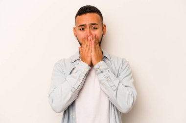 Beyaz arka planda izole edilmiş genç İspanyol adam elleri endişeli bir şekilde ağzı örtüyor..