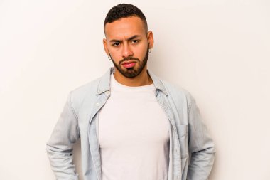 Genç İspanyol adam beyaz arka planda izole edilmiş üzgün, ciddi yüzlü, mutsuz ve hoşnutsuz..