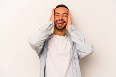 Beyaz arka planda izole edilmiş genç İspanyol adam ellerini başının üstünde tutarak neşeyle gülüyor. Mutluluk kavramı.