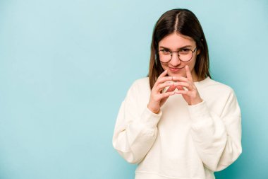 Kafkasyalı genç bir kadın mavi arka planda izole edilmiş bir plan kuruyor, bir fikir kuruyor..