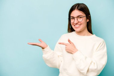 Mavi arka planda izole edilmiş beyaz bir kadın. Elinde palmiye ağacının fotokopisini tutarken heyecanlı..