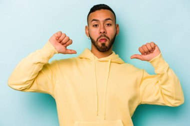 Mavi arka planda izole edilmiş genç bir İspanyol gururlu ve kendinden emin hissediyor, örnek olarak..