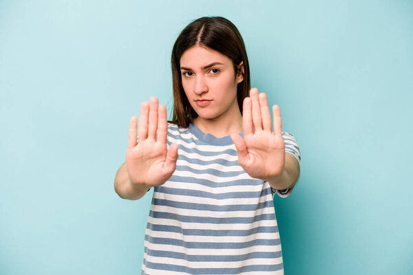 Young caucasian woman isolated on blue background standing with outstretched hand showing stop sign, preventing you.