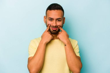 Latin kökenli genç bir adam mavi arka planda iki seçenek arasında kuşkulanıyor..