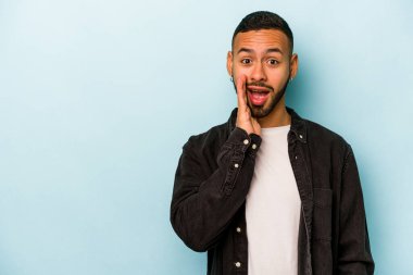 Mavi arka planda izole edilmiş genç bir İspanyol yüksek sesle bağırıyor, gözleri açık ve elleri gergin tutuyor..