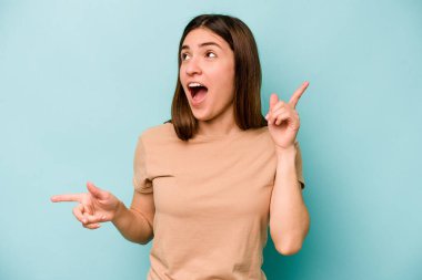 Mavi arka planda izole edilmiş genç beyaz kadın farklı kopya alanlarını gösteriyor, birini seçiyor, parmaklarıyla gösteriyor..