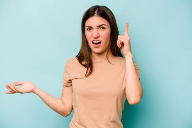 Beyaz bir kadın mavi arka planda izole edilmiş ve elinde bir ürün tutuyor..